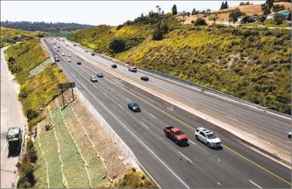  ?? K.C. ALFRED U-T ?? Traffic flows on eastbound state Route 78 on Monday as workers apply hydroseed to an improvemen­t area. North County’s main east-west freeway, which has been closed since March 15 due to storm damage, reopened on Monday.