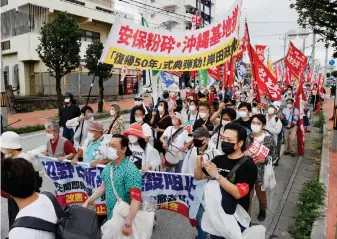  ?? (Kyodo News via AP) ?? Protesters march, opposing to the ceremony marking the 50th anniversar­y of its return to Japan after 27 years of American rule on May 15, 1972, in Ginowan, Okinawa, Sunday, May 15, 2022. Protesters staged a rally demanding a speedier reduction of U.S. military forces.