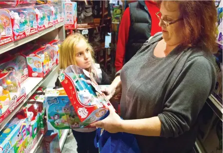  ?? BEBETO MATTHEWS/AP ?? Cinnamon Boffa, right, from Bensalem, Pa., checks out a “Chubby Puppies” toy for her daughter Serenity, left, at a Toys R Us, in New York. With some holiday toys already in stores, shoppers may want to start planning their strategy.