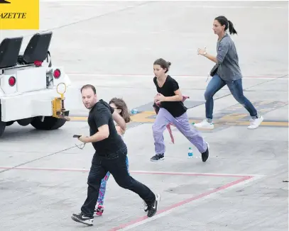  ?? WILFREDO LEE / THE ASSOCIATED PRESS ?? People run on the tarmac at Fort Lauderdale-Hollywood Internatio­nal Airport on Friday, after a shooter opened fire inside a terminal of the airport, killing five people and wounding several others before being taken into custody.