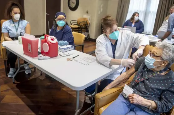  ?? Alexandra Wimley/Post-Gazette ?? Ruth Lindner, 97, right, gets her first dose of the Pfizer-BioNTech COVID-19 vaccine from CVS Pharmacy nurse Sandy Dodd on Saturday at the Juniper Village at Forest Hills senior living home. Resident care aid Gabrielle Ikper, far left, and nurse Cynthia Currie look on.