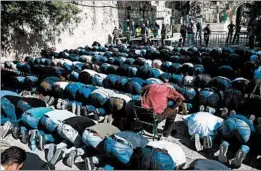  ?? AHMAD GHARABLI/GETTY-AFP ?? Muslims pray Sunday near the entrance of a holy site that Israel reopened after a deadly Friday attack. Some worshipper­s refused to enter because of new security measures.