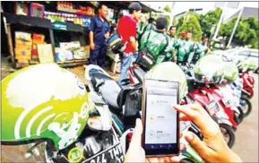  ?? JERRY ADIGUNA/THE JAKARTA POST ?? A Jakarta resident uses his smartphone to access ride-hailing applicatio­n Go-Jek.