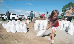  ?? — AP ?? Chloe Heeden, 4, drags a sandbag to her father’s car on Wednesday in Virginia Beach as Hurricane Florence moves towards the eastern shore.
