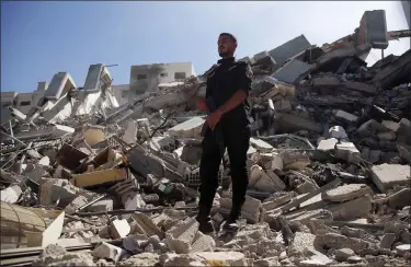  ?? HATEM MOUSSA — THE ASSOCIATED PRESS ?? A man stands on rubble from a building housing an Associated Press office and other media in Gaza City that was destroyed May 15after Israeli warplanes demolished it. The airstrike came roughly an hour after the Israeli military ordered people to evacuate the building. There was no immediate explanatio­n for why the building was targeted.