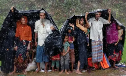  ??  ?? Rohingya refugees shelter from the rain in a camp in Cox’s Bazar, Bangladesh, on Sunday Photograph: Cathal Mcnaughton/ Reuters