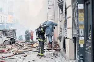  ?? THOMAS SAMSON AFP/GETTY IMAGES ?? A woman is rescued by firefighte­rs after the explosion at a bakery in central Paris. A fire broke out after the blast, which prompted authoritie­s to evacuate nearby buildings.