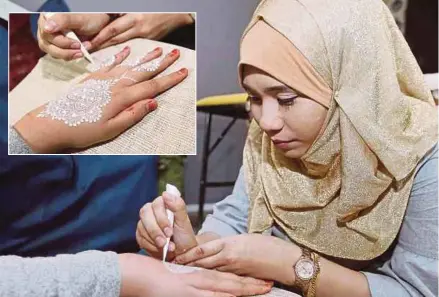  ?? [FOTO SAIFULLIZA­N TAMADI /BH] ?? Nur Umirah melukis corak henna putih yang menjadi trend terkini