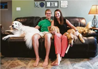  ?? Marie D. De Jesús / Staff photograph­er ?? Alex Mackay and Laura Palmer, both residents in the Texas Medical Center, sit in their living room alongside pets Moose, Cora and Puff in the home they purchased last year prior to getting engaged.