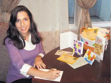  ?? GRANT MULLIGAN/GIRLS LOVE MAIL ?? Author Gina Mulligan, founder of Girls Love Mail, at her dining room table beside a basket filled with the letters she received during her treatment.