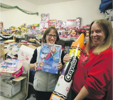  ??  ?? Gayle Ireland, left, and Karen Birtwistle stand in a packed toy room at the Goldstream Food Bank as they prepare to distribute Christmas Hampers this year.