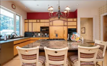  ?? ?? The island, with a granite countertop and a breakfast bar, is the centerpiec­e of the kitchen and is lit by a chandelier.