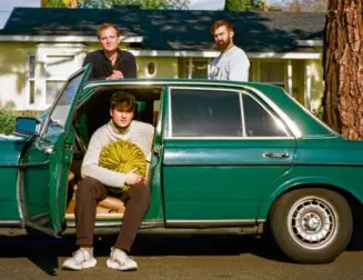  ?? SINNA NASSERI/NYT ?? Ezra Koenig (seated) with his Vampire Weekend bandmates Chris Baio (left) and Chris Tomson in Burbank, Calif., last month. The band has returned with their fifth studio album, “Only God Was Above Us.”