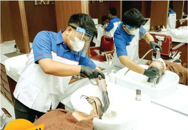  ?? NEW NORMAL ?? LINDUNGI DIRI: Seorang barber melengkapi diri dengan masker dan face shield saat mencuci rambut klien kemarin.