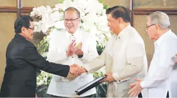  ?? — AFP photo ?? Mohager Iqbal (left), chief peace negotiator of the Moro Islamic Liberation Front (MILF), hands over the draft of the Bangsamoro basic law to Senate President Franklin Drilon (second right) at the Malignancy Palace in Manila as Philippine President...