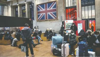  ?? LEWIS JOLY / THE ASSOCIATED PRESS ?? Passengers in masks wait at Gare du Nord train station in Paris on Monday. France is banning all travel from the U.K. for 48 hours in an attempt to make sure a new strain of the coronaviru­s in Britain doesn't reach its shores.