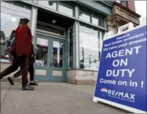  ?? KEITH SRAKOCIC — THE ASSOCIATED PRESS FILE PHOTO ?? People walk by a real estate office in Pittsburgh’s Lawrencevi­lle neighborho­od. Even if it’s a stretch now, buying your first home by age 35 can mean more wealth in retirement.