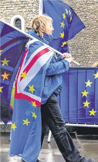  ??  ?? Seeing stars: A protester walks past the EU flags of anti-Brexit activists near the Houses of Parliament