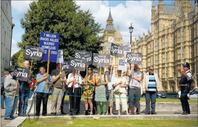  ?? MATT DUNHAM/ THE ASSOCIATED PRESS ?? Demonstrat­ors gather Thursday in London outside the Houses of Parliament to show opposition to military action against Syria. Organized by the Stop the War coalition, the protest was timed to coincide with a debate and vote by the House of Commons,...