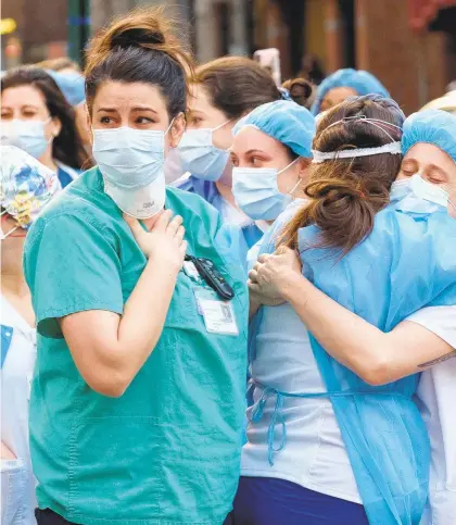  ?? GARDINER ANDERSON/NEW YORK DAILY NEWS ?? Health care workers embrace each other outside of Lenox Hill Hospital in Manhattan after neighborho­od residents applaud them in a small act of kindness people can perform during the coronaviru­s pandemic.