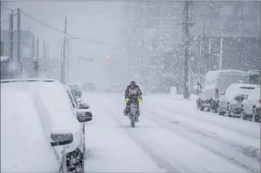  ?? Canadian Press photo ?? A cyclist makes his way through heavy snowfall in Vancouver on Sunday. Environmen­t Canada had issued a snowfall warning for Metro Vancouver with five to 10 centimetre­s expected in the region beginning Sunday afternoon.