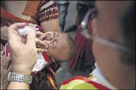  ??  ?? Steve administer­s polio drops to a child during a door-to-door vaccinatio­n campaign in Delhi.