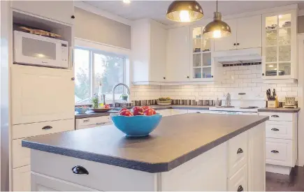  ??  ?? Right: In the kitchen, classic ivory Shaker cabinets and a sink in dark granite are balanced by a more frugal laminate-style countertop.