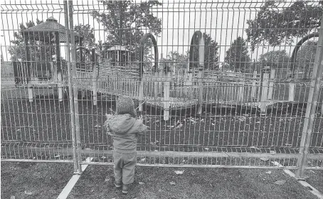  ?? DAN JANISSE ?? Two-year-old Weylin Kimble could only look through a fence that was erected around an accessible playground at Lacasse Park in Tecumseh on Wednesday. The playground was destroyed by fire on Tuesday, and a 13-year-old boy has been charged.