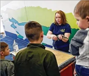  ?? ADAM CAIRNS / DISPATCH ?? Colby Halker, an intern working with animals at COSI in Columbus, shows off a baby alligator named Tic Tock to children visiting on Wednesday.