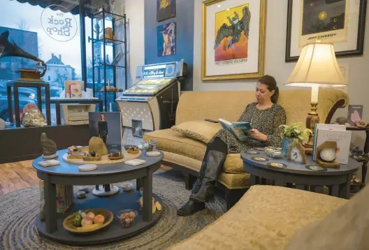  ?? THE ROCK SHOP ?? Store co-owner Laura Bruni reads at The Rock Shop in Homewood, where patrons can find vinyl records and guitars, crystals, gems and minerals, as well as the expertise to craft them into jewelry and, as the joint home of Bookies independen­t bookstore, an array of reading materials.