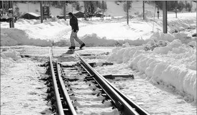  ?? FABRICE COFFRINI / AGENCE FRANCE-PRESSE ?? A road services employee walks past snow covered railways at the ski resort of Taesch on Wednesday near Zermatt, Switzerlan­d.