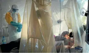  ?? AP ?? Health workers wearing protective gear check on a patient isolated in a plastic cube at an Ebola treatment centre in Beni, Congo.