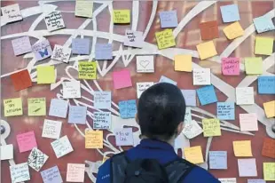  ?? Jeff Chiu Associated Press ?? LEESHA ZIEBER looks at notes at a San Francisco BART station Nov. 14. Writer Muriel MacDonald said she started the project to help people deal with the aftermath of the election.