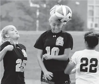  ?? AMY DAVIS/BALTIMORE SUN ?? Archbishop Spalding Ella Bjorn heads the ball between teammate Jenna Snead, left, and Notre Dame Prep’s Alex Fava during a showdown of unbeaten teams in the IAAM A Conference. The win helped the Cavaliers improve to 9-0-1 overall and 5-0 in the conference.