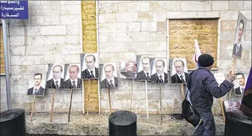  ?? PHOTOS BY MUZAFFAR SALMAN / ASSOCIATED PRESS 2013 ?? Photos of Russian President Vladimir Putin and Syrian President Bashar Assad are propped against a wall in front of the Russian Embassy in Damascus in 2013. Putin is winning plaudits from many Syrians and Iraqis, who see Russia’s military interventi­on...