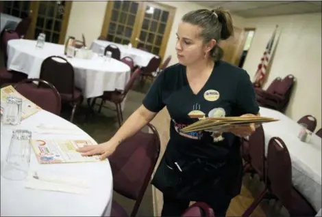  ?? ROGER NOMER — THE JOPLIN GLOBE VIA AP ?? Shawna Green, waitress at Granny Shaffer’s, puts out menus for customers at the restaurant in Joplin, Mo. Wages will be increasing for millions of lowincome workers across the U.S. as the new year ushers in new laws in numerous states. In Missouri and Arkansas, minimum wages are rising as a result of voter-approved ballot initiative­s.