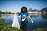  ?? (File Photo/AP/Bruna Prado) ?? A volunteer collects garbage June 5 from the banks of the Rodrigo de Freitas Lagoon marking World Environmen­t Day in Rio de Janeiro.