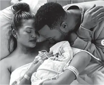  ??  ?? Heartache: The star cradles her dead baby, Jack, with husband John legend