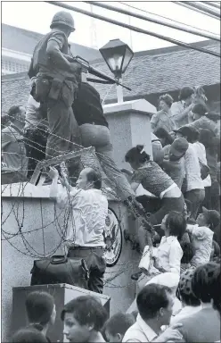  ?? NEAL ULEVICH/ ASSOCIATED PRESS ARCHIVES ?? On April 29, 1975, people scale the 14- foot wall of the U. S. Embassy in Saigon, Vietnam.