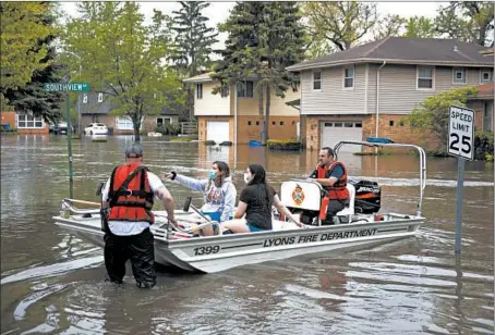  ?? ERIN HOOLEY/CHICAGO TRIBUNE PHOTOS ?? Lyons firefighte­rs ferry Maria Quintero and her sister, also Maria Quintero, on Monday after heavy rains flooded homes in Brookfield.