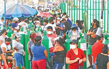  ?? — AFP photo ?? People wait to refill oxygen tanks in a queue of up to 200 people who camp outside a production plant, in San Juan de Lurigancho, Lima.