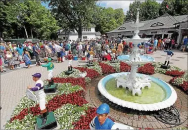  ?? PHOTOS PROVIDED BY SPENCER TULIS ?? Racing fans wait at the Clubhouse entrance Friday as the first day of Saratoga’s Thoroughbr­ed Summer Meet got underway July 22. In the foreground are the fountain with lawn jockeys adorned with all the Grade I winner’s silks colors from last year’s meet.