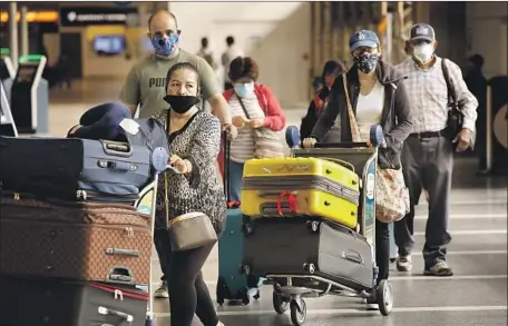  ?? Al Seib Los Angeles Times ?? TRAVELERS at Los Angeles Internatio­nal Airport on May 11 wear face coverings. Airlines, not federal regulators, require them.