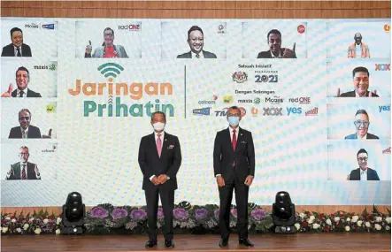  ??  ?? We’re with you: Muhyiddin (left) posing with Tengku Zafrul, with the virtual participat­ion of 11 representa­tives from local telco operators at the launch of the Jaringan Prihatin programme in Putrajaya. — Bernama