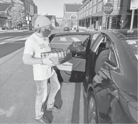  ?? MIKE SNIDER/ USA TODAY ?? Conor Provost of Bluejacket brewery in Washington, D. C., puts beer in a car. The brewpub now takes beer and food orders online or by phone and will deliver to customers at the curbside, as well as delivering to homes.