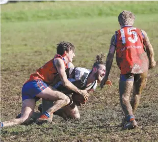  ??  ?? Buln Buln’s Jake Baker lays a strong tackle on Poowong’s Jaemeel Knect, while Brandon Allen waits for the ball to spill out