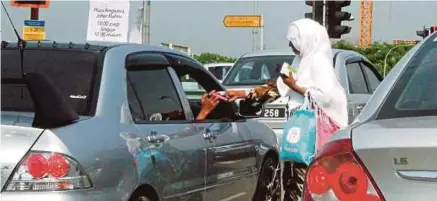  ?? [FOTO ZAIN AHMED/BH] ?? Pengemis dipercayai warga asing meminta sedekah sambil menjual tisu berhampira­n lampu isyarat Jalan Skudai ke Plaza Angsana Johor Bahru.