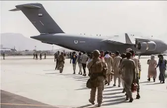  ?? Sgt. Samuel Ruiz / U.S. Marine Corps ?? Marines escort evacuees to a U.S. Air Force transport at Hamid Karzai Internatio­nal Airport in Kabul. Thousands are still trying to flee Afghanista­n a week after the Taliban takeover.