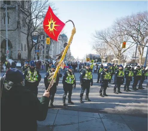 ?? Errol Mcgihon / Postmedia News Files ?? A man carrying a Mohawk Warrior Flag faces a line of Parliament­ary Protective Service officers
at the All Eyes on Parliament: Rally for the Wet’suwet’en in downtown Ottawa on Feb. 24.