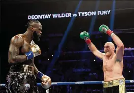  ?? HARRY HOW / GETTY IMAGES ?? Tyson Fury (right) baits Deontay Wilder in the second round, fighting to a draw during the WBC heavyweigh­t championsh­ip at Staples Center on Dec. 1. Fury could have a rematch with Wilder and fight Anthony Joshua this year.